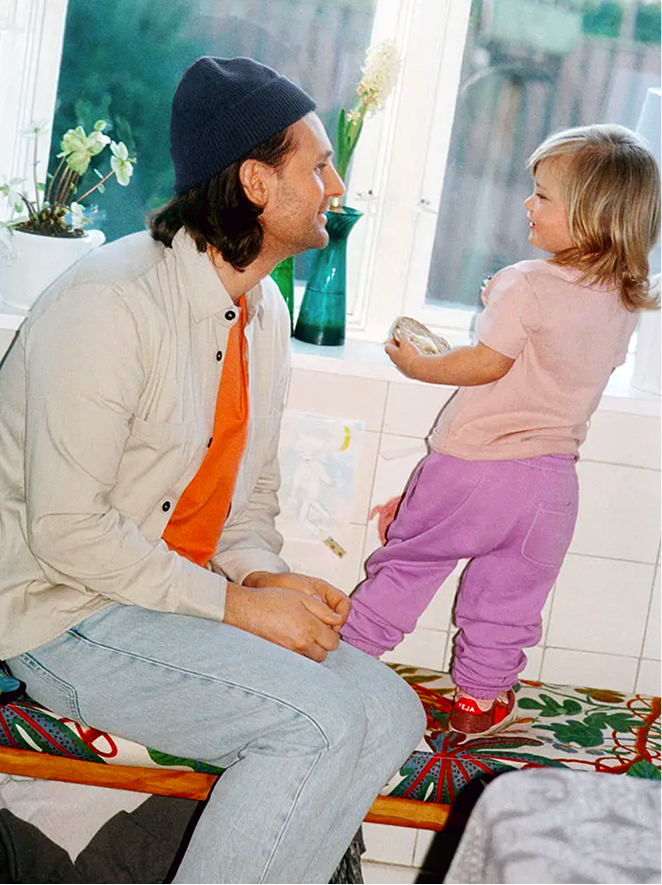 A father and his young daughter laughing together in a sunlit kitchen